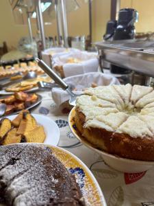 a table topped with plates of cakes and pastries at Hotel Dallas in Penha