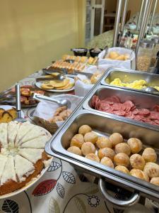una línea de buffet con diferentes tipos de comida en una mesa en Hotel Dallas, en Penha