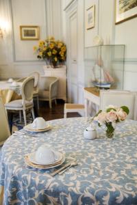a table with plates and a vase of flowers on it at Malouinière Le Valmarin in Saint Malo
