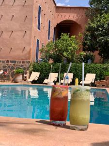 dos bebidas están sentadas junto a una piscina en Riad Malak en Ouirgane