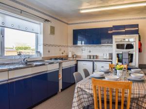 a kitchen with blue cabinets and a table with chairs at Trem Y Werydd in Amlwch