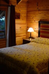um quarto com uma cama, um candeeiro e uma janela em La Solita em Villa La Angostura