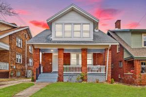 a red brick house with a white porch at Charming 3-Bedroom Home Near Downtown Free Parking in Pittsburgh