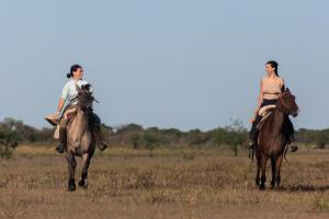 two women riding on horses in a field at Rincón del Socorro in Uguay