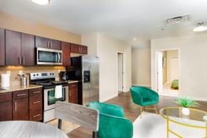 a kitchen with wooden cabinets and green chairs at Luxe City Views in DT Pittsburgh VALET GYM WIFI in Pittsburgh