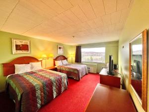 a hotel room with two beds and a television at Lively Inn and Suites - Sudbury in Naughton