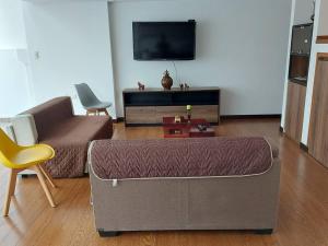 un soggiorno con divano e TV a schermo piatto di Departamento nuevo, elegante y muy cómodo. a Loja
