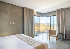 um quarto com uma cama e uma cadeira e uma grande janela em Chateaux del Valle Vacational Homes em Valle de Guadalupe
