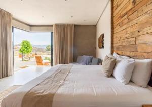 1 dormitorio con 1 cama grande y pared de madera en Chateaux del Valle Vacational Homes en Valle de Guadalupe