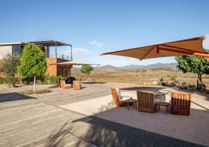 a patio with chairs and a table and an umbrella at Chateaux del Valle Vacational Homes in Valle de Guadalupe