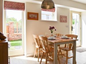 a dining room with a table and chairs and a window at White Heather Barn in Swanwick