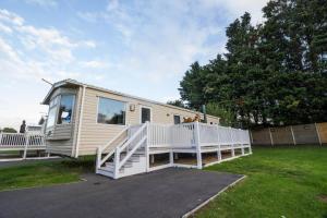 uma casa móvel com um alpendre e um corrimão branco em 8 Berth Caravan At Orchards Haven In Clacton-on-sea, Essex Ref 15007o em Clacton-on-Sea