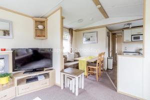 uma sala de estar caravana com uma televisão e uma mesa em 8 Berth Caravan At Orchards Haven In Clacton-on-sea, Essex Ref 15007o em Clacton-on-Sea