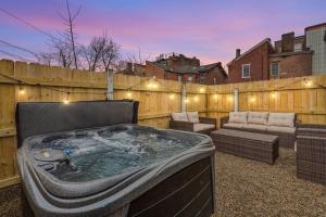 NEW! High-end Manchester Home w/ a hot tub في بيتسبرغ: حوض استحمام ساخن في الفناء الخلفي مع سياج خشبي