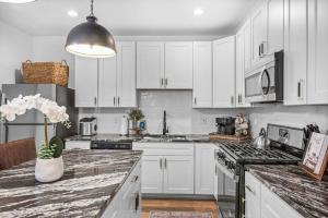 a kitchen with white cabinets and a vase of flowers on the counter at NEW! High-end Manchester Home w/ a hot tub in Pittsburgh