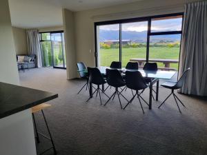 a dining room with a table and chairs and a large window at Ben Ohau Views On The Drive in Twizel