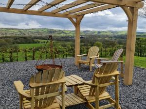 two chairs and a swing on a patio with a pergola at Sewin Cottage in Carmarthen