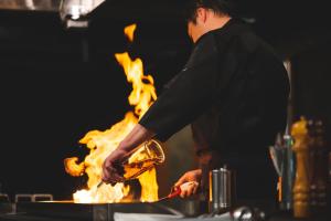 Ein Mann kocht vor dem Feuer in der Unterkunft Atarayo Nishiizu Onsen in Izu