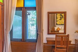 ハーンドンにあるมนต์เมืองเชียงใหม่ รีสอร์ต Monmuang Chiangmai Resortの窓、鏡、椅子が備わる客室です。