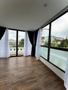 um quarto com janelas do chão ao tecto e pisos em madeira em Memory Inn Dalat em Da Lat