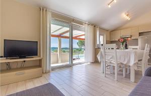 a living room with a television and a table with chairs at Awesome Home In Pomer With House Sea View in Pomer