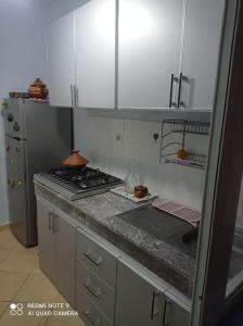a kitchen with white cabinets and a stove top oven at Bel appartement à 5min de la plage in Tangier