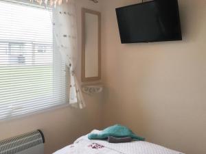 a bedroom with a flat screen tv on the wall at Casabella in Hemsby
