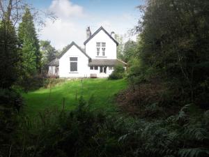 ein weißes Haus auf einem Hügel mit einem grünen Hof in der Unterkunft The Secret Garden in Windermere