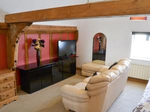 a living room with a couch and a tv at Clamp Farm Barn in Stowmarket