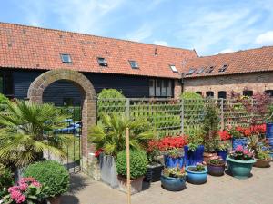 a garden with potted plants in front of a building at Clamp Farm Barn in Stowmarket