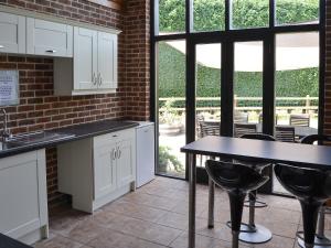 a kitchen with white cabinets and a table with chairs at Clamp Farm Barn in Stowmarket