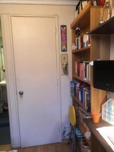 Habitación con baño privado في سانتياغو: باب أبيض في غرفة مع رف كتاب