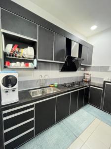 a kitchen with black and white cabinets and a sink at DRest Homestay Desa Aman 