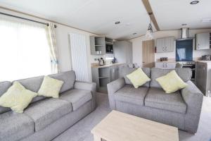 ein Wohnzimmer mit 2 Sofas und einer Küche in der Unterkunft Beautiful 6 Berth Caravan With Full Sea Views For Hire In Suffolk Ref 68002cr in Lowestoft