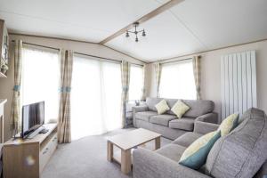 ein Wohnzimmer mit einem Sofa und einem TV in der Unterkunft Beautiful 6 Berth Caravan With Full Sea Views For Hire In Suffolk Ref 68002cr in Lowestoft