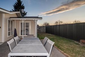 a table and chairs in a backyard with a fence at Relax on Rata, Cottage 1 in Twizel