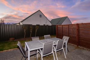 a table and chairs on a patio with a fence at Relax on Rata, Cottage 1 in Twizel