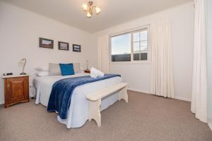 a white bedroom with a bed and a window at Relax on Rata, Cottage 1 in Twizel