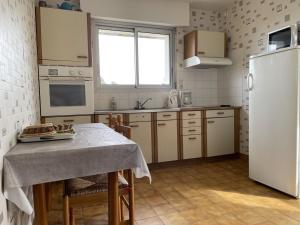 kuchnia ze stołem i białą lodówką w obiekcie Maison 3 pièces, vue Ria d'Étel, jardin clos, proche mer et plages - FR-1-397-71 w mieście Locoal-Mendon +6 zdjęć
