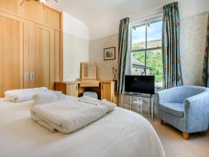 a bedroom with a bed and a tv and a chair at Greenbank in Keswick