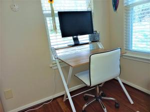 a computer desk with a monitor and a chair at Master Bedroom with King Bed-FREE-WiFi-Snack-Parkg in Relaxing Oasis in San Marcos