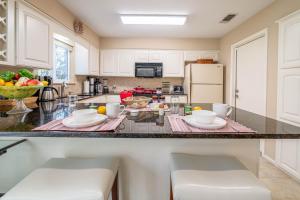 a kitchen with white cabinets and a counter with chairs at Master Bedroom with King Bed-FREE-WiFi-Snack-Parkg in Relaxing Oasis in San Marcos