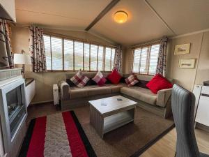 een woonkamer met een bank en een tafel bij Lovely Caravan With Decking Free Wifi At North Denes Caravan Park Ref 40145nd in Lowestoft