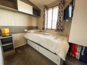 a small bedroom with a bed and a window at Lovely Caravan With Decking Free Wifi At North Denes Caravan Park Ref 40145nd in Lowestoft