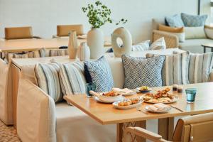 a table with plates of food on it with couches at Eastin Grand Hotel Phayathai in Bangkok