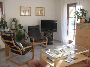 Adelhausen的住宿－堅果樹下公寓，客厅配有两把椅子、一张桌子和一台电视