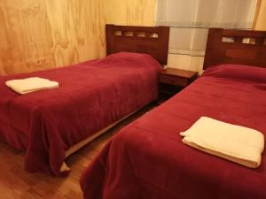 2 camas en una habitación con sábanas rojas y toallas blancas en Cabañas Candelaria, en Los Ángeles