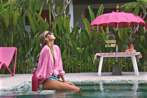 a woman sitting in the water next to a table with an umbrella at PinkCoco Gili Air - for Cool Adults Only in Gili Air