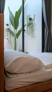 a bedroom with a bed and a window with a plant at Khanh Thy Homestay Lagi in La Gi