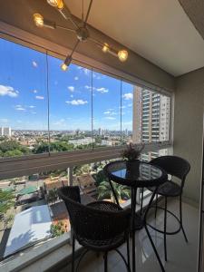 a balcony with a table and chairs and a large window at Apartamento Luxo St Bueno in Goiânia